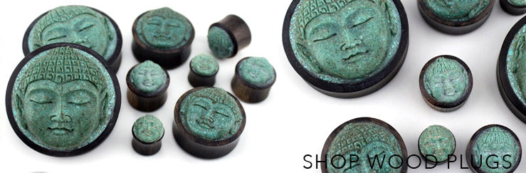 Dark wood plugs with carved green Buddha faces in many sizes, labeled Shop Wood Plugs