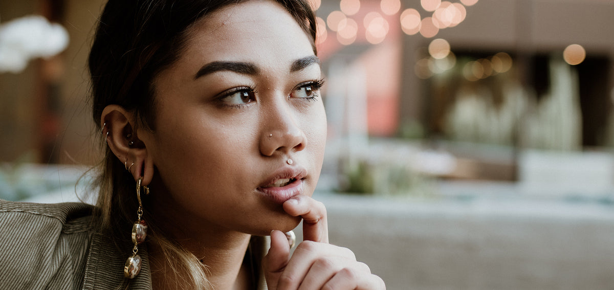 Woman with helix hoops and long beaded drop earrings, plus a nostril stud and a stud above her upper lip