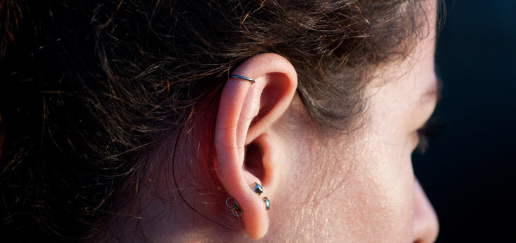 Ear with a thin hoop in the upper helix and two small pieces of jewelry in the lobe