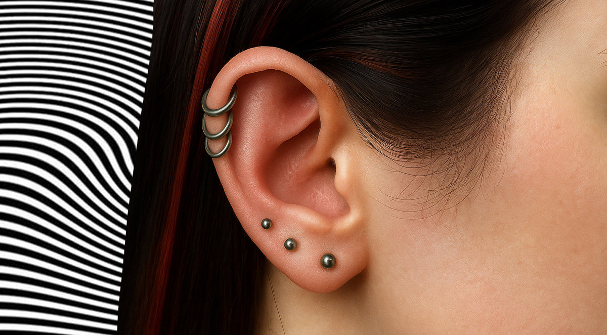Ear with three stacked silver-tone hoops along the upper helix and three graduated studs along the lobe