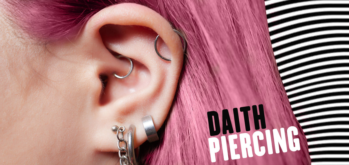 Text reading Daith Piercing beside an ear with silver-tone hoops in the daith and helix, framed by pink hair
