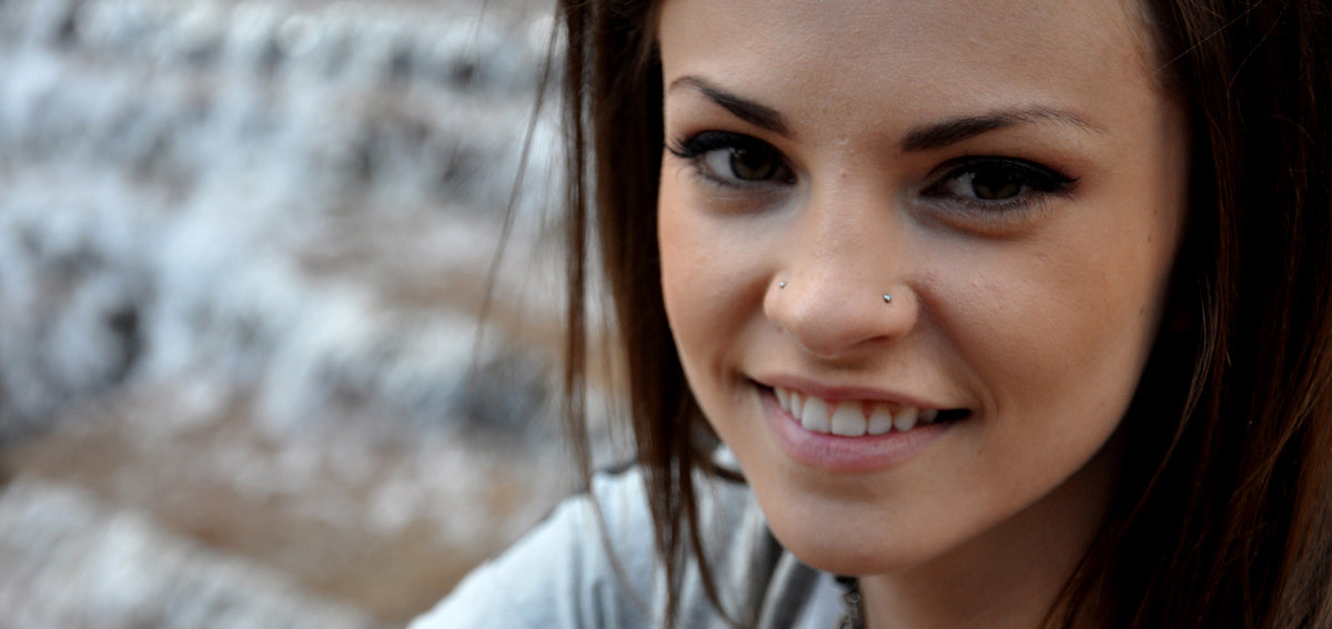 Smiling woman with long brown hair wearing a small stud in each nostril