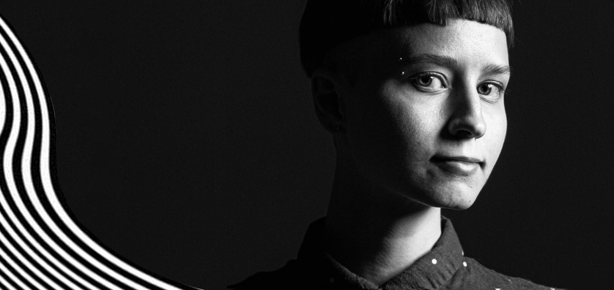 Black and white portrait of a person with short bangs and an eyebrow barbell