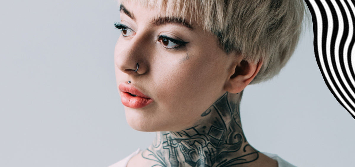 Woman with short platinum hair and neck tattoos wearing a stud above her upper lip and a nostril hoop