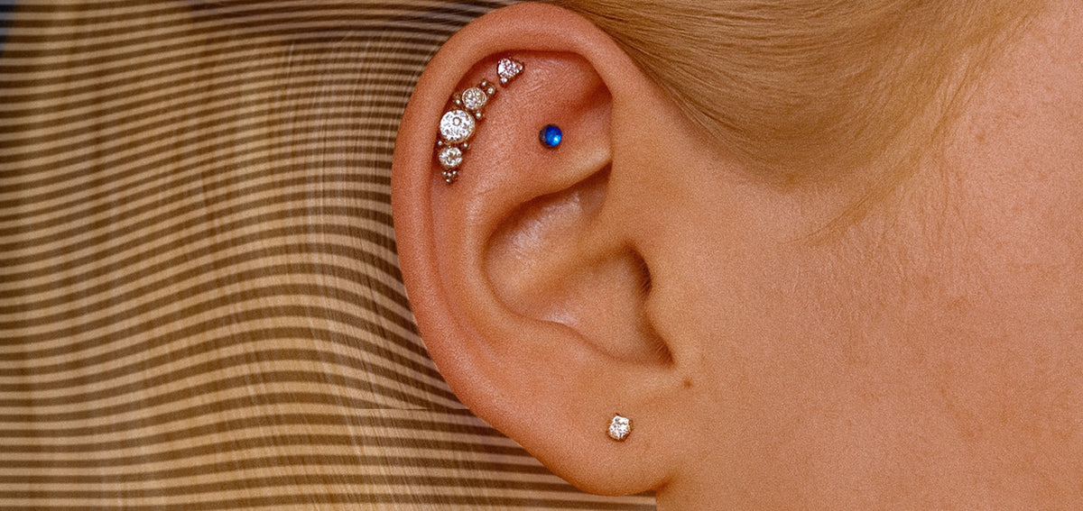 Ear with a curved crystal cluster along the upper helix, a blue gem stud below it and a small crystal lobe stud
