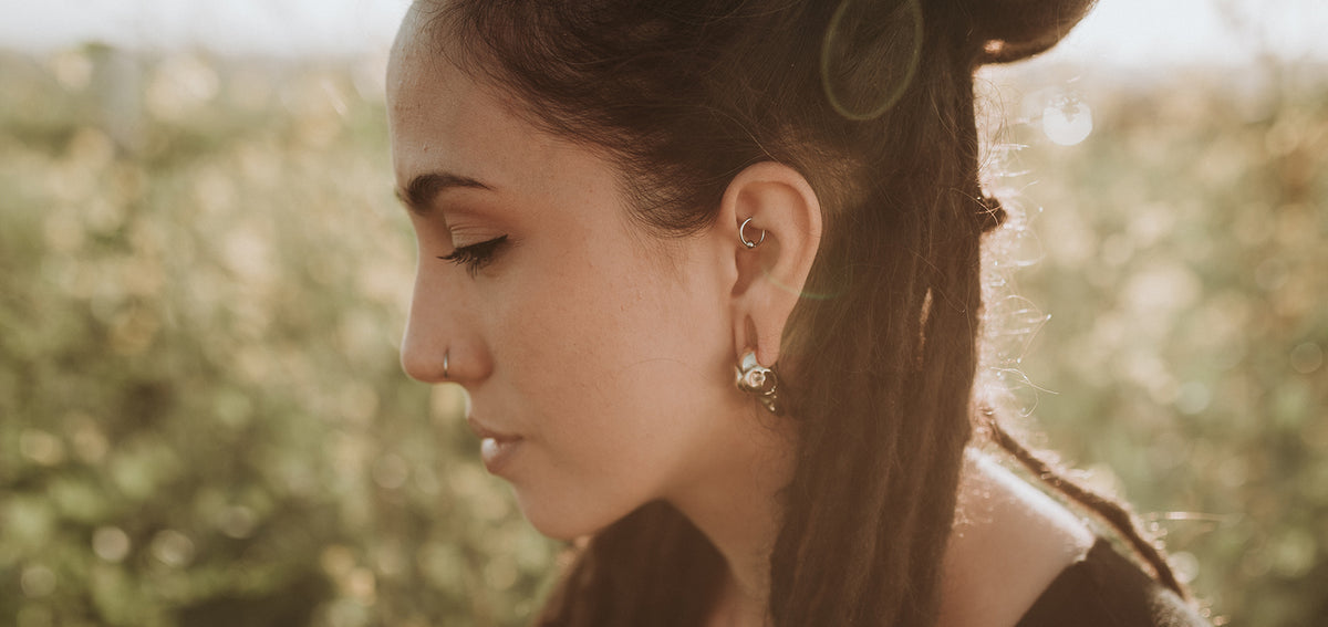 Woman in profile wearing a rook ring, a silver-tone earring in her lobe and a small nostril stud