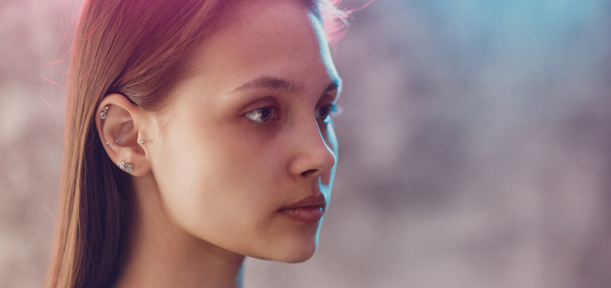 Woman in profile with a crystal helix stud, studs in her inner cartilage and tragus, and two crystal lobe studs