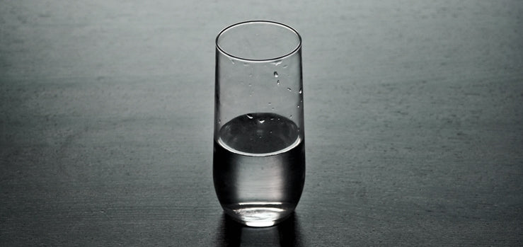 Glass half full of water on a dark table