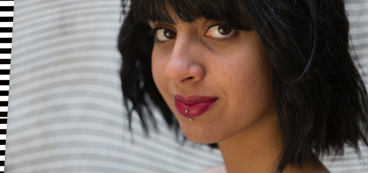 Woman with a black bob and red lipstick wearing a silver-tone vertical labret through her lower lip