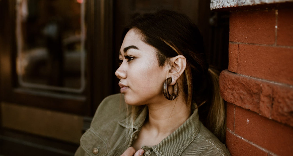 Woman in profile wearing a dark wooden hoop in a stretched earlobe