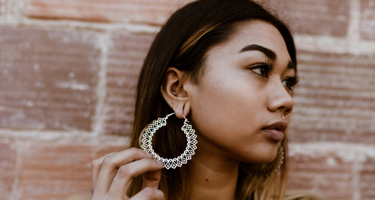 Woman wearing a large silver filigree hoop, a nose stud and several ear piercings